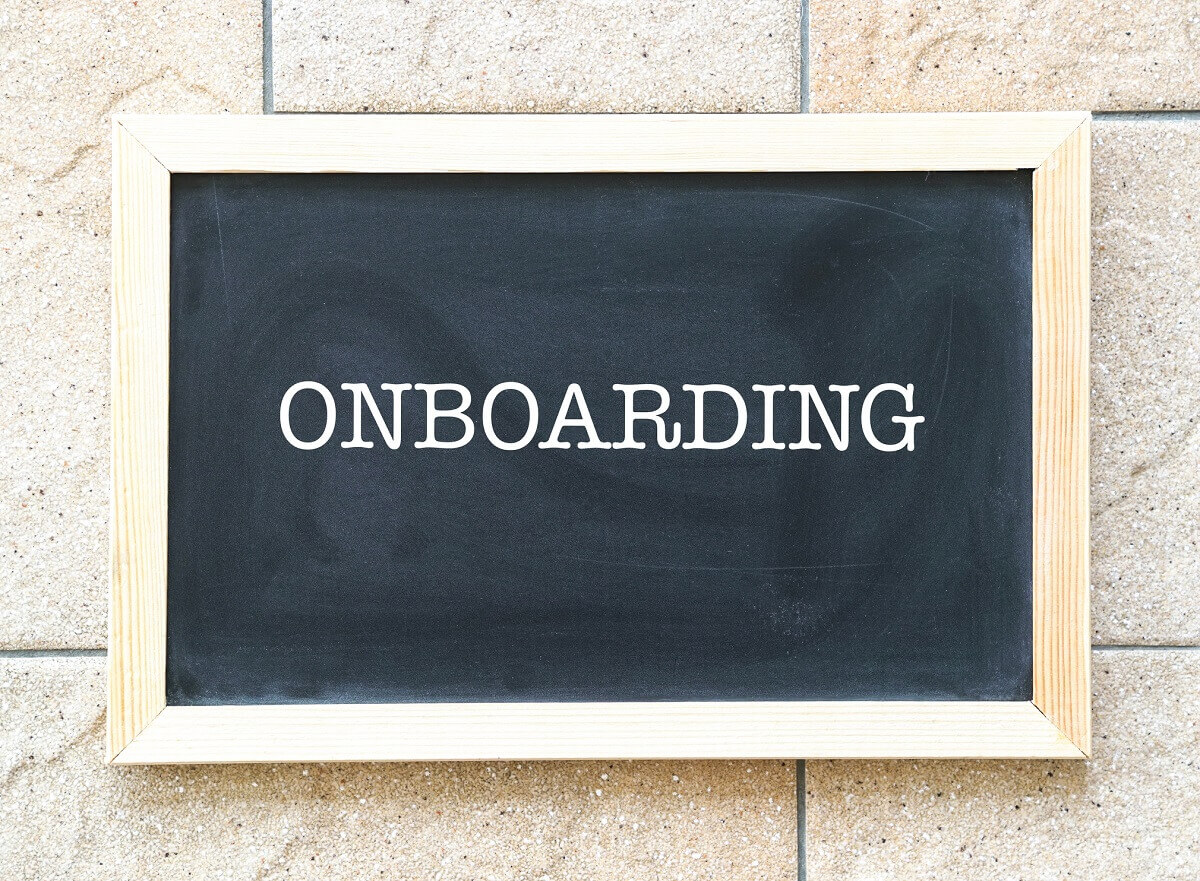 Auf einer Mauer hängt eine Tafel auf der geschrieben steht "Onboarding".