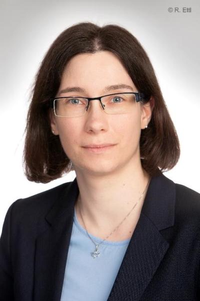 Daniela Rojatz Das Foto zeigt Daniela Rojatz. Eine Frau mit dunklen kinnlangen Haaren. Hellem Hautton und einer Brille. Sie trägt ein blaue Bluse und einen schwarzen Blazer.